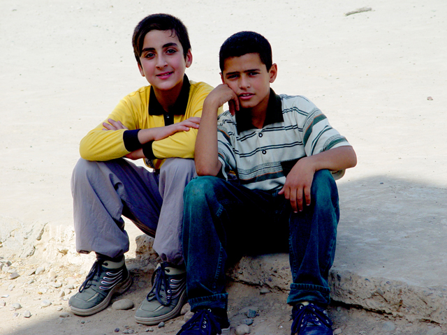 Two Boys Sitting In A Balad Playground